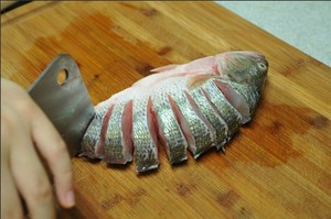 將鱸魚清洗干凈，從脊椎處切斷至腹部，腹部保留1cm左右不要切斷。