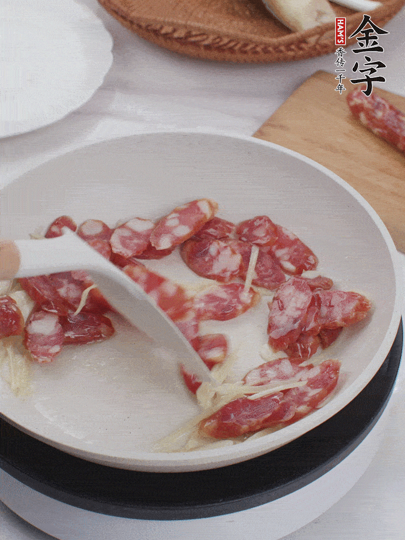 油溫3成熱時(shí)，下姜絲、蒜片、香腸炒出油脂。