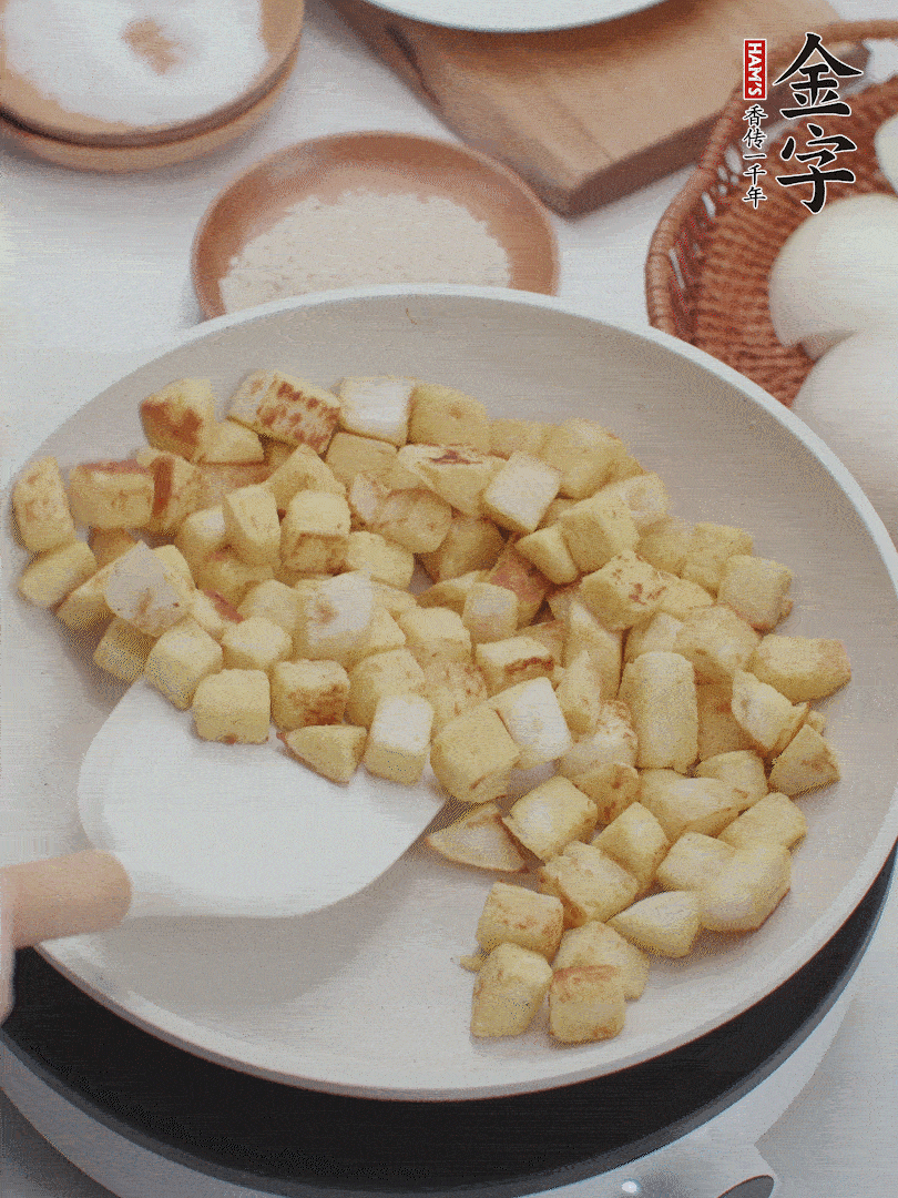 起鍋熱油，倒入饅頭丁，小火煎至蛋液凝固定型再翻面，饅頭丁部煎至金黃時盛起待用。