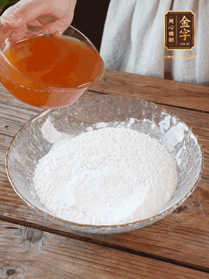 轉(zhuǎn)化糖漿、枧水、花生油攪拌均勻，加入面粉混合，醒發(fā)2小時(shí)。捏成23g一個(gè)的小球